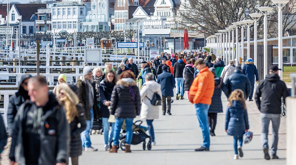 Leute sind am Samstagvormittag auf der Promenade von Travemünde unterwegs. / Foto: Markus Scholz/dpa