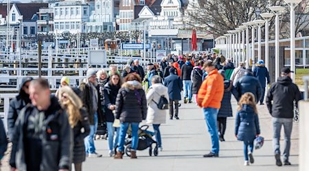 Leute sind am Samstagvormittag auf der Promenade von Travemünde unterwegs. / Foto: Markus Scholz/dpa