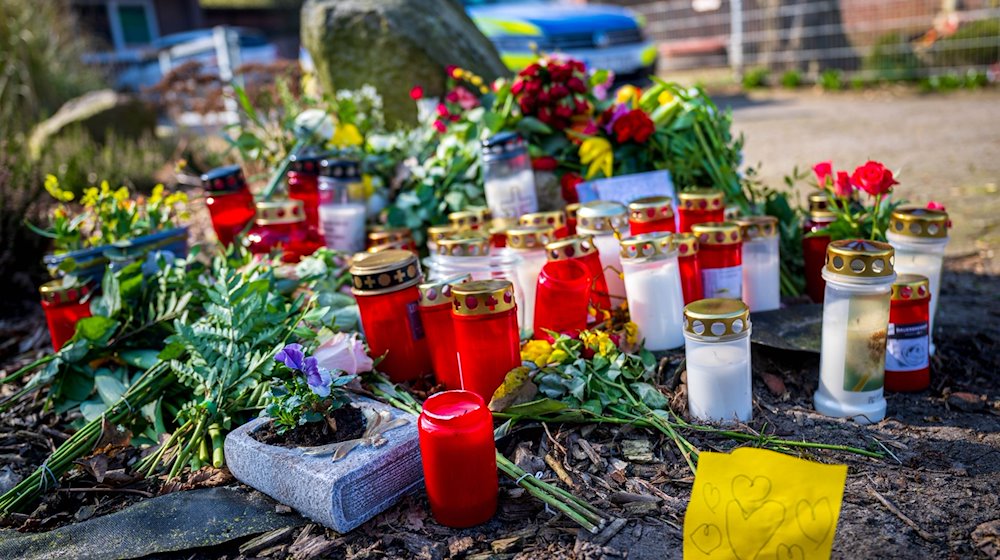 Blumen und Kerzen liegen vor einem Einfamilienhaus. / Foto: Sina Schuldt/dpa