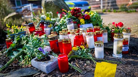 Blumen und Kerzen liegen vor einem Einfamilienhaus. / Foto: Sina Schuldt/dpa