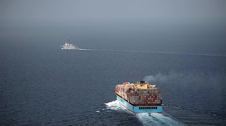 Ein US-Lenkwaffenzerstörer begleitet ein Handelsschiff, das mit Containern beladen ist. / Foto: Logan C. Kellums/US Navy/dpa/Archivbild