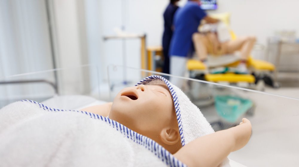 Der Dummy eines Säuglings liegt in einem Bettchen im Simulationslabor vom Studiengang Hebammenwissenschaft. / Foto: Friso Gentsch/dpa