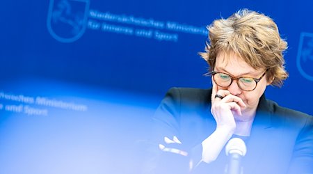 Daniela Behrens (SPD), Innenministerin von Niedersachsen, blickt auf einer Pressekonferenz zur Polizeilichen Kriminalstatistik Niedersachsen 2022 auf ihre Unterlagen - im Vordergrund leuchtet das Display einer Fernsehkamera. / Foto: Moritz Frankenberg/dpa