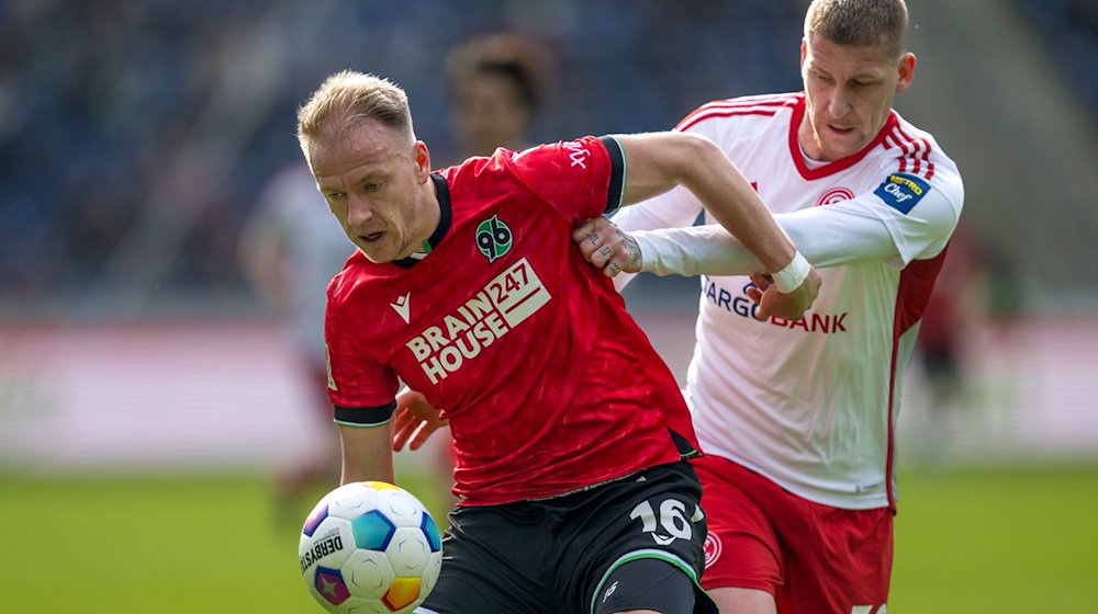 Hannovers Havard Nielsen (l) und Düsseldorfs Jordy de Wijs kämpfen um den Ball. / Foto: David Inderlied/dpa