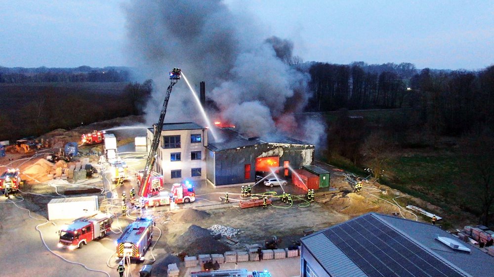 Einsatzkräfte der Feuerwehr löschen den Großbrand einer Gewerbehalle in Alfhausen. / Foto: Ulf Zurlutter/Nord-West-Media TV/dpa