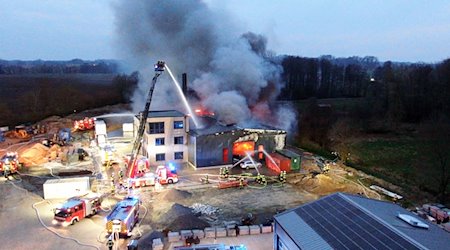 Einsatzkräfte der Feuerwehr löschen den Großbrand einer Gewerbehalle in Alfhausen. / Foto: Ulf Zurlutter/Nord-West-Media TV/dpa