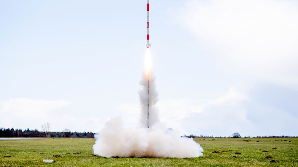 Eine mit mehreren Minisatelliten bestückte Rakete startet 2023 von einer Wiese auf dem Flugplatz. / Foto: Hauke-Christian Dittrich/dpa