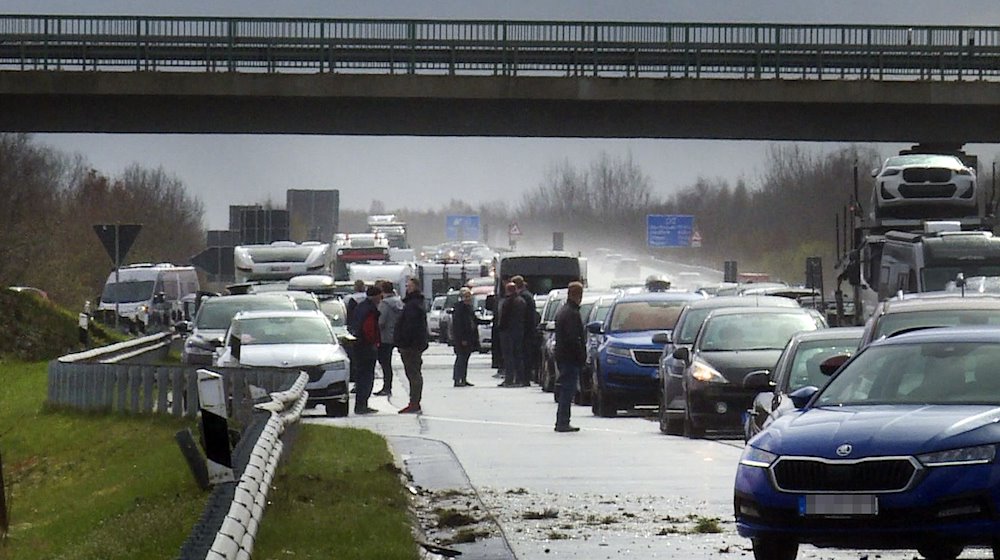 Fahrzeuge und Menschen stehen nach mehreren Unfällen auf der Fahrbahn der A31. / Foto: -/NWM-TV/dpa