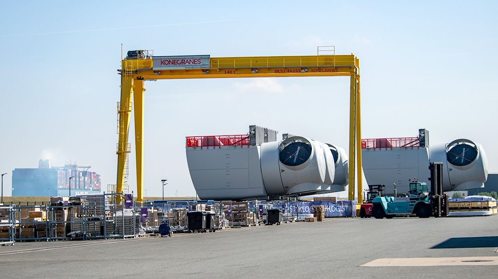 Ein Containerschiff fährt an den Offshore-Maschinenhäusern auf dem Werkgelände von Siemens Gamesa in Cuxhaven vorbei. / Foto: Sina Schuldt/dpa