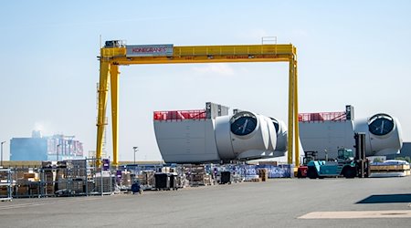 Ein Containerschiff fährt an den Offshore-Maschinenhäusern auf dem Werkgelände von Siemens Gamesa in Cuxhaven vorbei. / Foto: Sina Schuldt/dpa