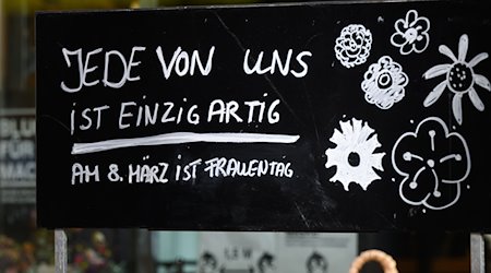 Ein Schriftzug „Jede von ist einzigartig - Am 8. März ist Frauentag“ steht auf einem Schild vor einem Blumenladen. / Foto: Julian Stratenschulte/dpa