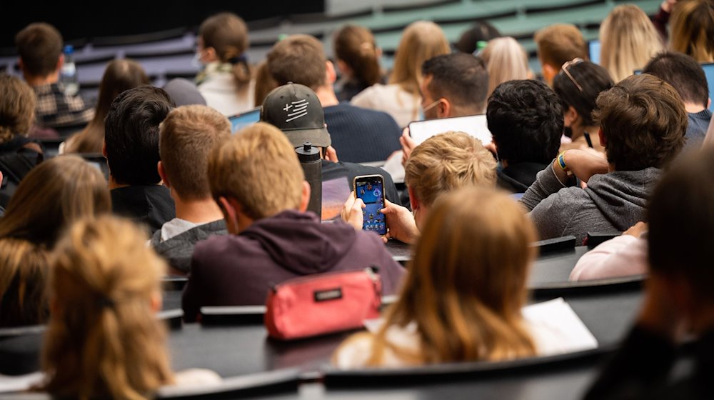 Ein Student spielt am Smartphone während einer Vorlesung. / Foto: Julian Stratenschulte/dpa