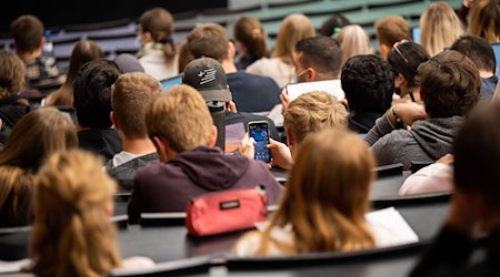 Ein Student spielt am Smartphone während einer Vorlesung. / Foto: Julian Stratenschulte/dpa