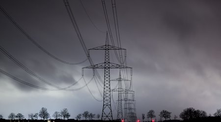 Dunkle Wolken ziehen über eine Hochspannungsleitung hinweg. / Foto: Julian Stratenschulte/dpa