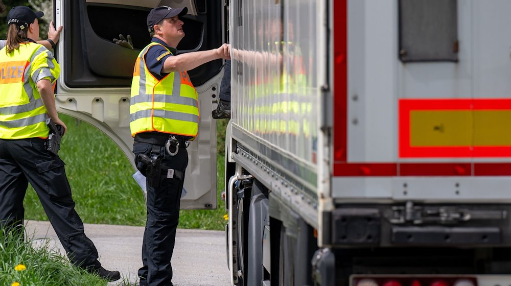 Polizisten überprüfen bei einer Verkehrskontrolle einen Lastwagen. / Foto: Armin Weigel/dpa