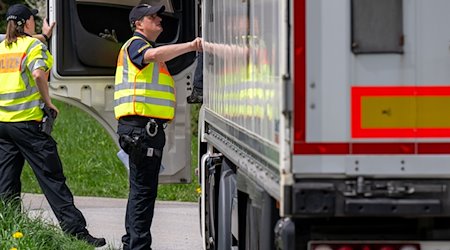 Polizisten überprüfen bei einer Verkehrskontrolle einen Lastwagen. / Foto: Armin Weigel/dpa