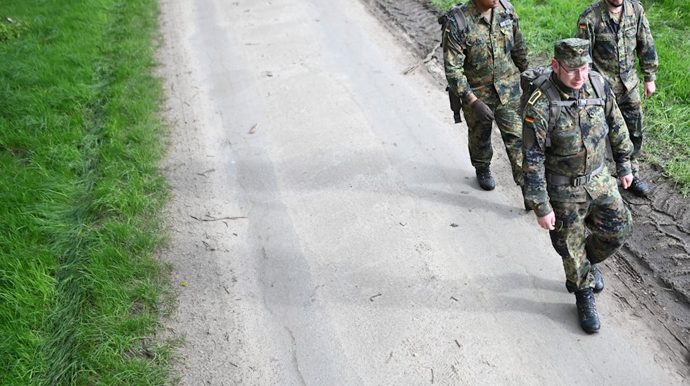 Soldaten der Bundeswehr gehen einen Waldweg entlang, nachdem sie ein Waldstück abgesucht haben. / Foto: Lars Penning/dpa