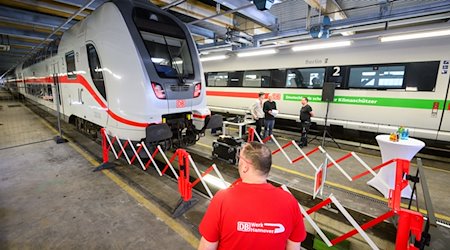 Ein Mitarbeiter der Deutschen Bahn steht im Werk Hannover neben einem IC2 Doppelstock Intercity und einem ICE T. / Foto: Julian Stratenschulte/dpa