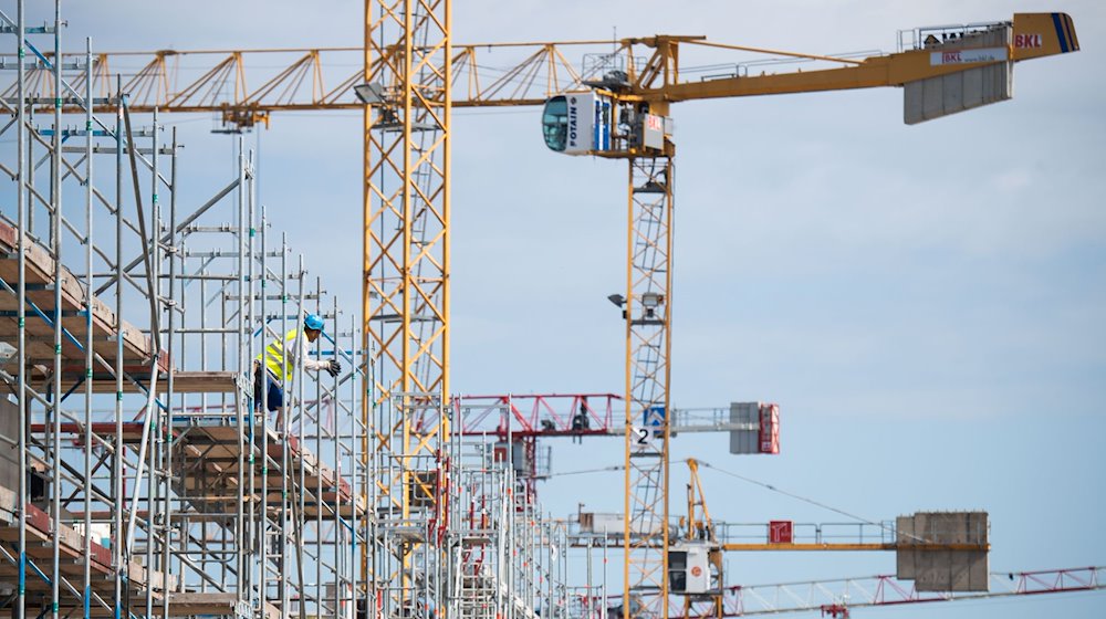 Ein Arbeiter steht auf einer Baustelle für Mehrfamilienhäuser auf einem Gerüst. / Foto: Julian Stratenschulte/dpa/Symbolbild