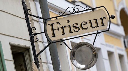 Ein Schild mit der Aufschrift «Friseur» hängt an einem Gebäude. / Foto: Monika Skolimowska/dpa-Zentralbild/ZB/Symbolbild