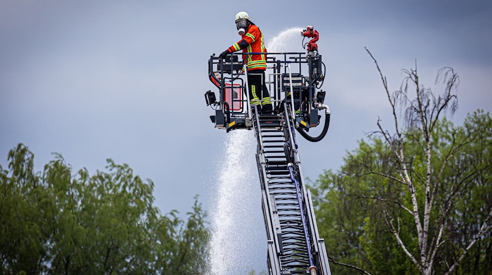 Einsatzkräfte der Feuerwehr löschen über eine Drehleiter einen Brand in einem Braunschweiger Industriegebiet. / Foto: Moritz Frankenberg/dpa
