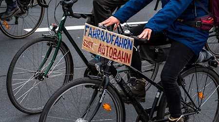 Bei einer Demo fährt ein Fahrradfahrer mit einem Schild mit der Aufschrift ««Fahrradfahr’n» statt Autobahn». / Foto: Christophe Gateau/dpa