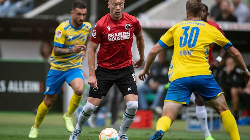 Hannovers Havard Nielsen (M) spielt gegen Braunschweigs Brian Behrendt (r). / Foto: Swen Pförtner/dpa