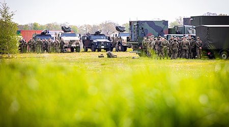 Soldaten der Bundeswehr besprechen sich am Bereitstellungsraum neben ihren Fahrzeugen. / Foto: Moritz Frankenberg/dpa