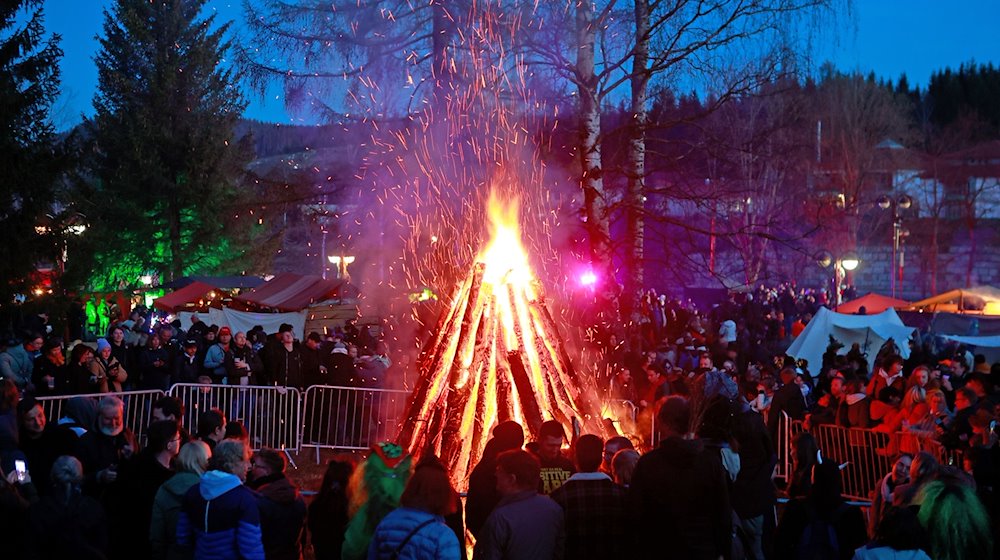 Besucher stehen auf dem Walpurgisfest in Schierke am Feuer. / Foto: Matthias Bein/dpa
