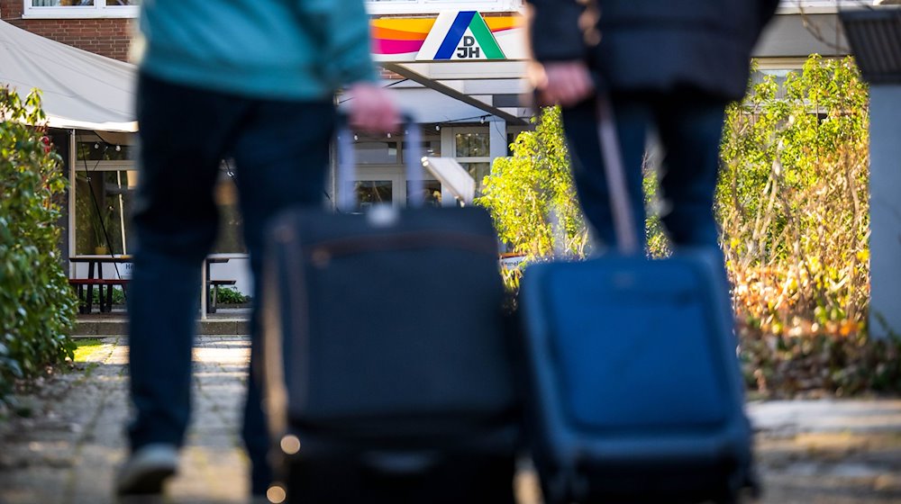 Gäste stehen mit Koffern und Taschen vor einer Jugendherberge. / Foto: Sina Schuldt/dpa/Symbolbild