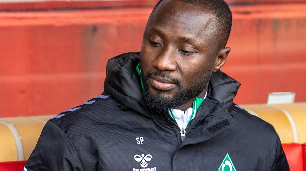 Naby Keita von Werder Bremen sitzt auf der Bank und blickt nach unten. / Foto: Andreas Gora/dpa