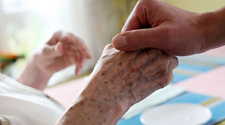 Ein Pfleger hält in einem Pflegeheim die Hand einer Bewohnerin. / Foto: Oliver Berg/dpa/Archivbild