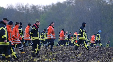 Feuerwehrleute laufen über einen Acker bei Bremervörde. / Foto: Markus Hibbeler/dpa