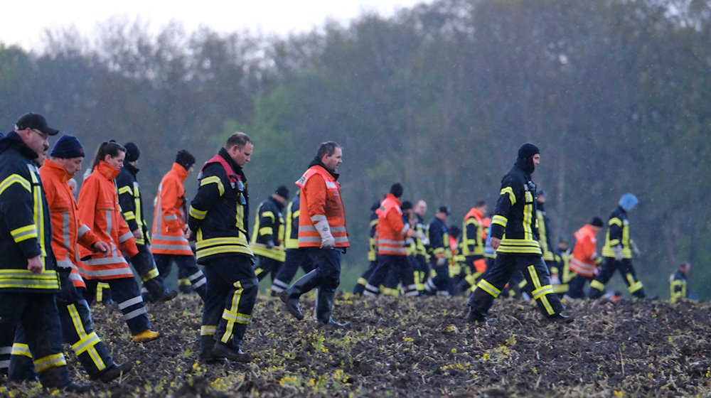Feuerwehrleute laufen über einen Acker bei Bremervörde. / Foto: Markus Hibbeler/dpa