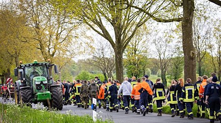Einsatzkräfte der Feuerwehr gehen eine Straße im Landkreis Stade entlang. / Foto: Moritz Frankenberg/dpa