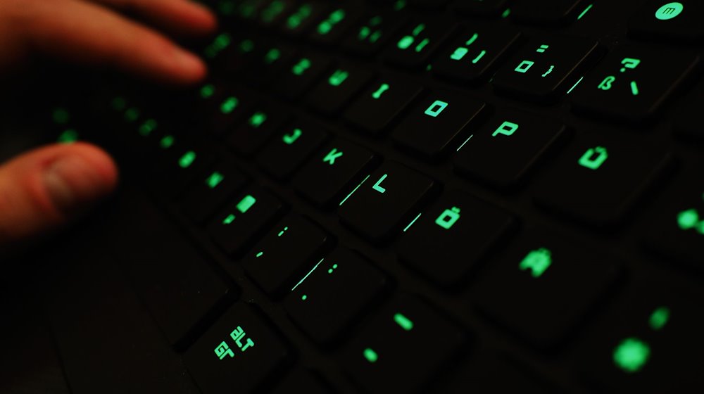 Ein Mann tippt auf einer beleuchteten Tastatur. / Foto: Nicolas Armer/dpa
