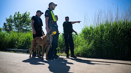 Einsatzkräfte der Polizei stehen bei der Suche nach dem vermissten Arian mit einem Spürhund an der Oste. / Foto: Sina Schuldt/dpa