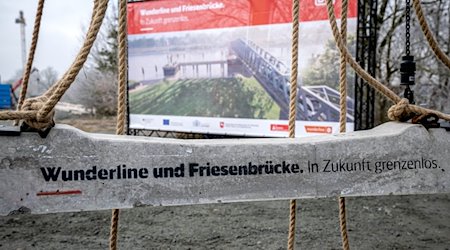 „Wunderlinie und Friesenbrücke“ steht auf einer Bahnschwelle, die auf der neuen Bahnstrecke verbaut wird. / Foto: Sina Schuldt/dpa