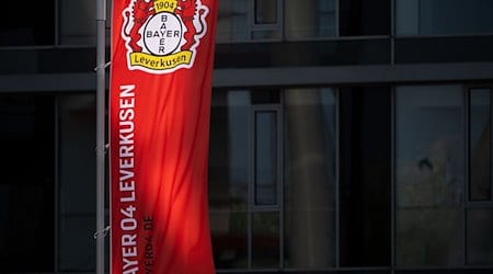 Eine Fahne weht vor der BayArena, dem Stadion des Fußball-Bundesligisten Bayer 04 Leverkusen, und wird dabei von der Sonne angeschienen. / Foto: Marius Becker/dpa