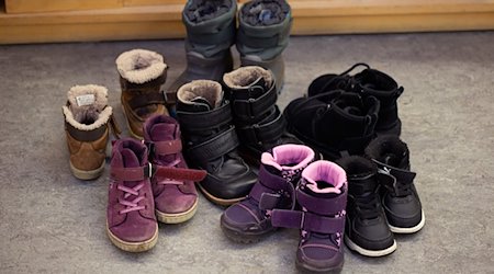 Kinderschuhe und -stiefel sind auf dem Boden in einer Kindertagesstätte abgestellt. / Foto: Friso Gentsch/dpa