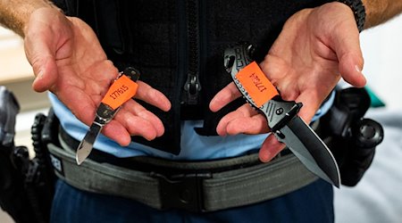 Ein Bundespolizist zeigt sichergestellte Messer. / Foto: Daniel Bockwoldt/dpa