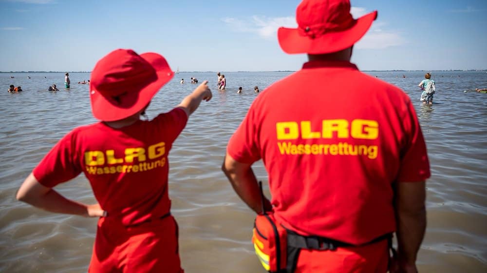 Mitglieder der DLRG (Deutsche Lebens-Rettungs-Gesellschaft) stehen am Strand von Dangast. / Foto: Sina Schuldt/dpa