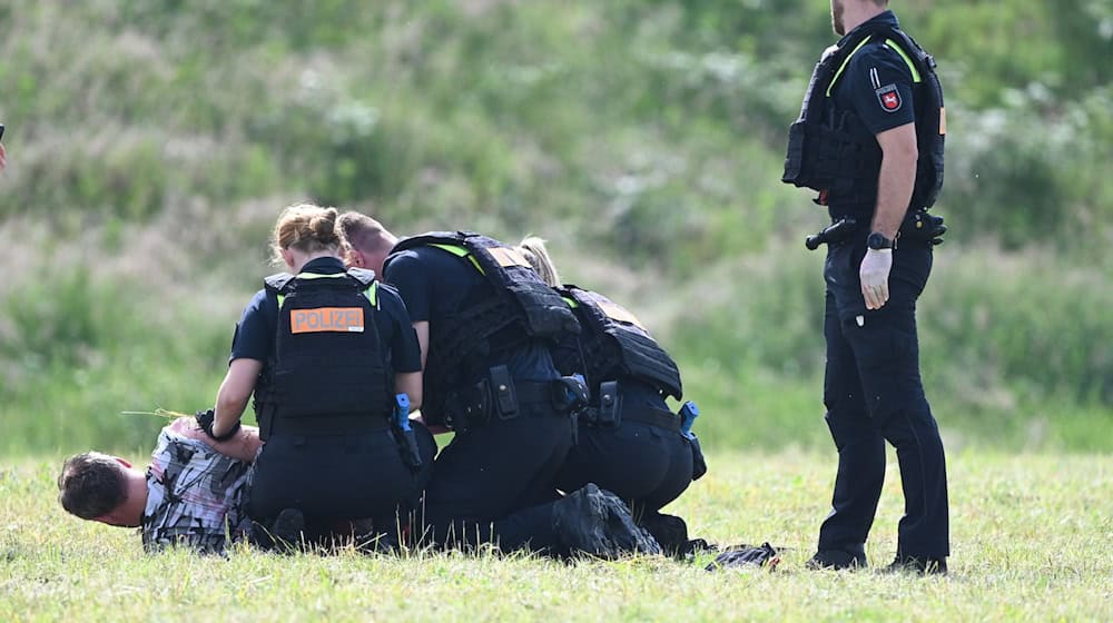 Polizisten stellen den mutmaßlichen Täter. / Foto: Lars Penning/dpa