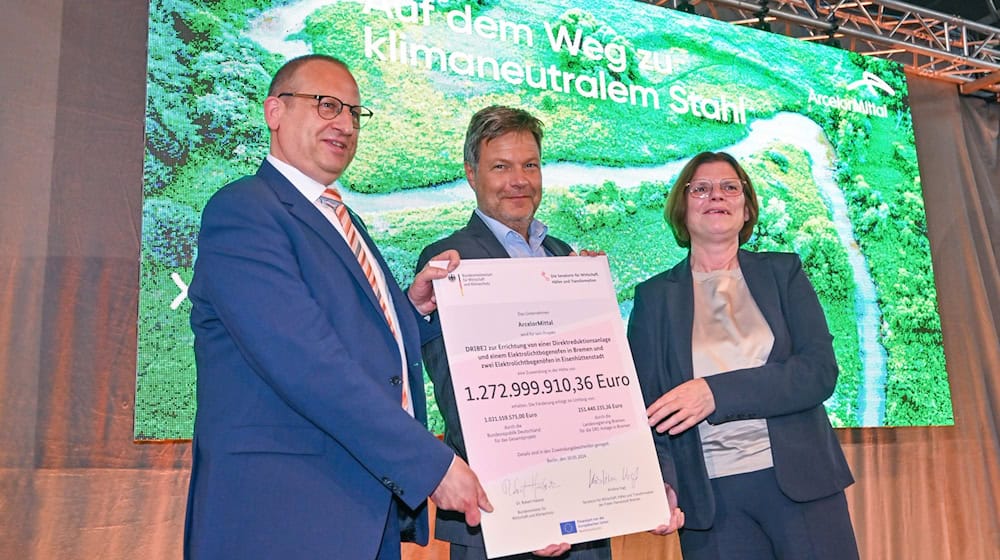 Thomas Bünger (l-r), CEO von ArcelorMittal, Robert Habeck (Grüne), Bundeswirtschaftsminister und Kristina Vogt (Die Linke), Bremer Senatorin für Wirtschaft, zeigen einen Fördermittelbescheid. / Foto: Patrick Pleul/dpa