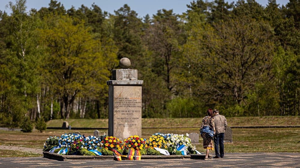 Zahlreiche Blumenkränze liegen um einen Gedenkstein auf dem Gelände der Gedenkstätte Bergen-Belsen. / Foto: Moritz Frankenberg/dpa