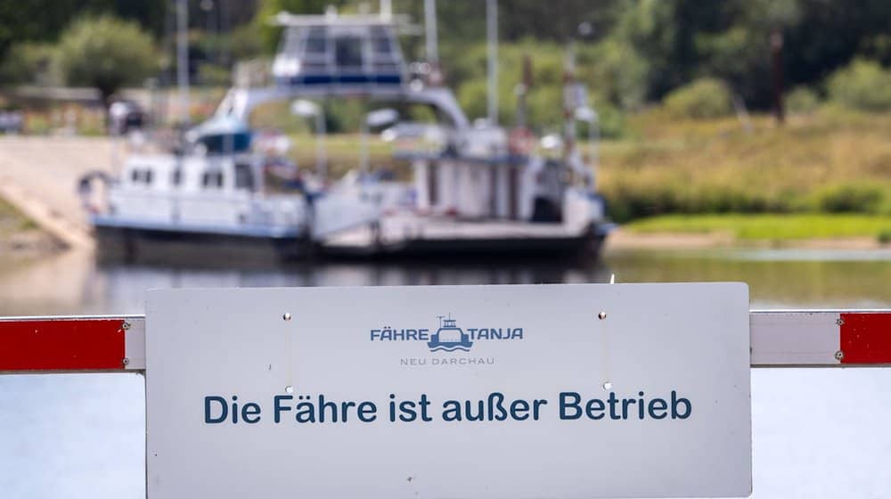 An einer Schranke hängt ein Schild mit der Aufschrift «Die Fähre ist außer Betrieb». / Foto: Jens Büttner/dpa