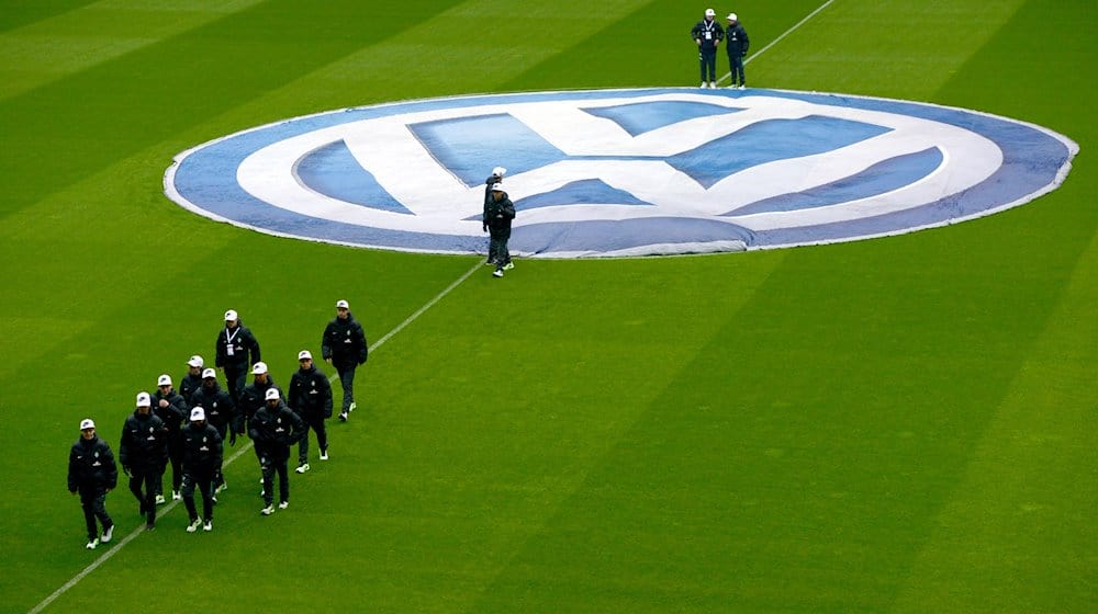 Balljungen verlassen nach dem Ausbreiten des Volkswagen-Logos vor dem Spiel den Platz. / Foto: David Hecker/dpa/Archivbild