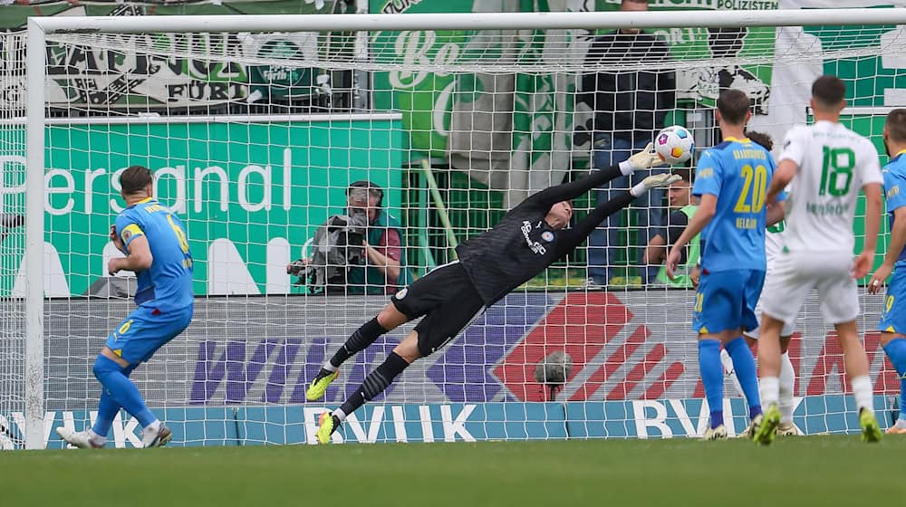 Torwart Ron Torben Hoffmann (M) von Eintracht Braunschweig kann einen Schuss mit den Fingersitzen zur Ecke klären. / Foto: Daniel Löb/dpa