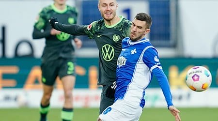Wolfsburgs Mattias Svanberg (M) und Darmstadts Fabian Schnellhardt (r) kämpfen um den Ball. / Foto: Uwe Anspach/dpa