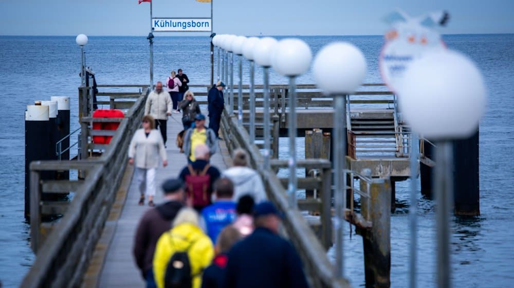 Spaziergänger sind auf der Seebrücke unterwegs. / Foto: Jens Büttner/dpa